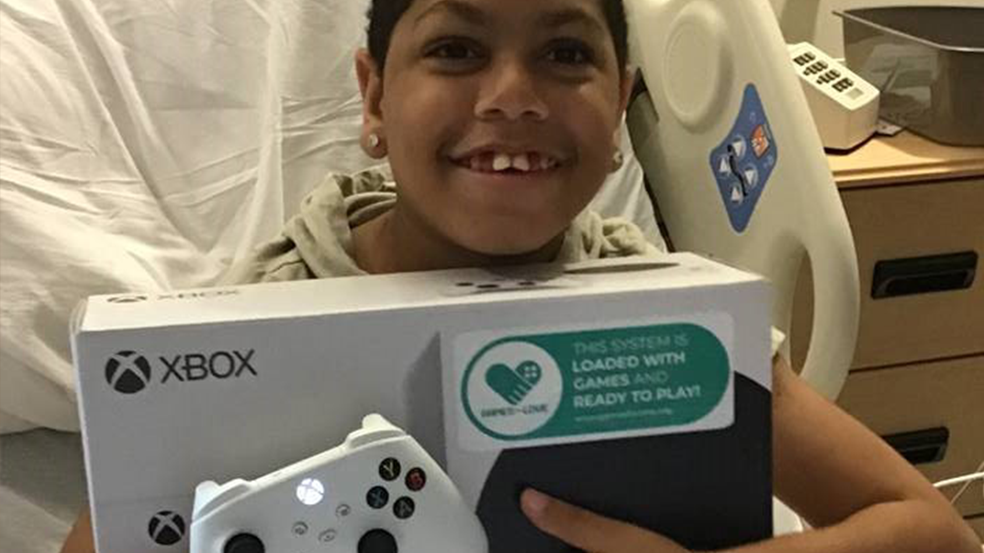 Child smiling with Xbox in hospital bed - Games For Love