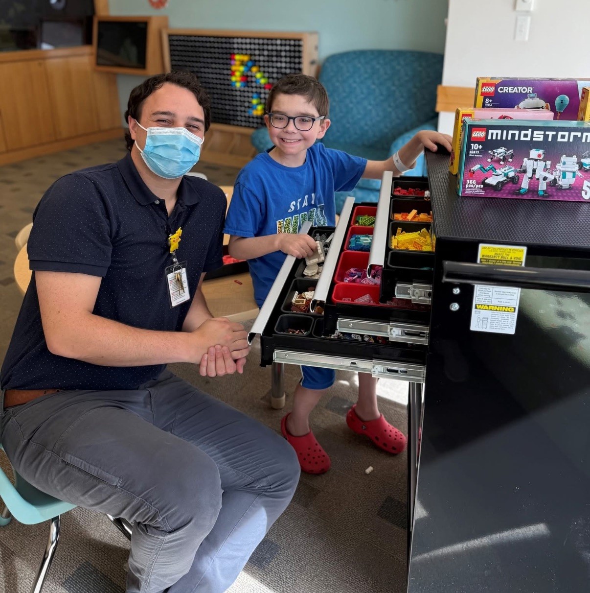 Child life specialist building LEGO with young patient